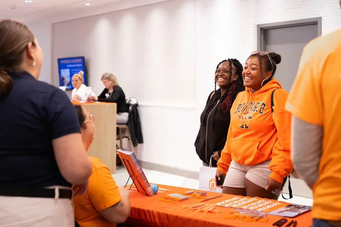 Two students outside of a Syracuse University abroad table during Welcome Week.